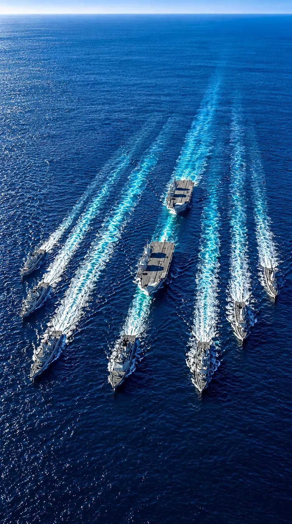 Aerial view of a naval fleet sailing in formation across deep blue ocean water